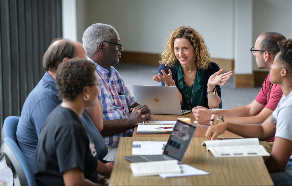Professor talks with students around a table during a class