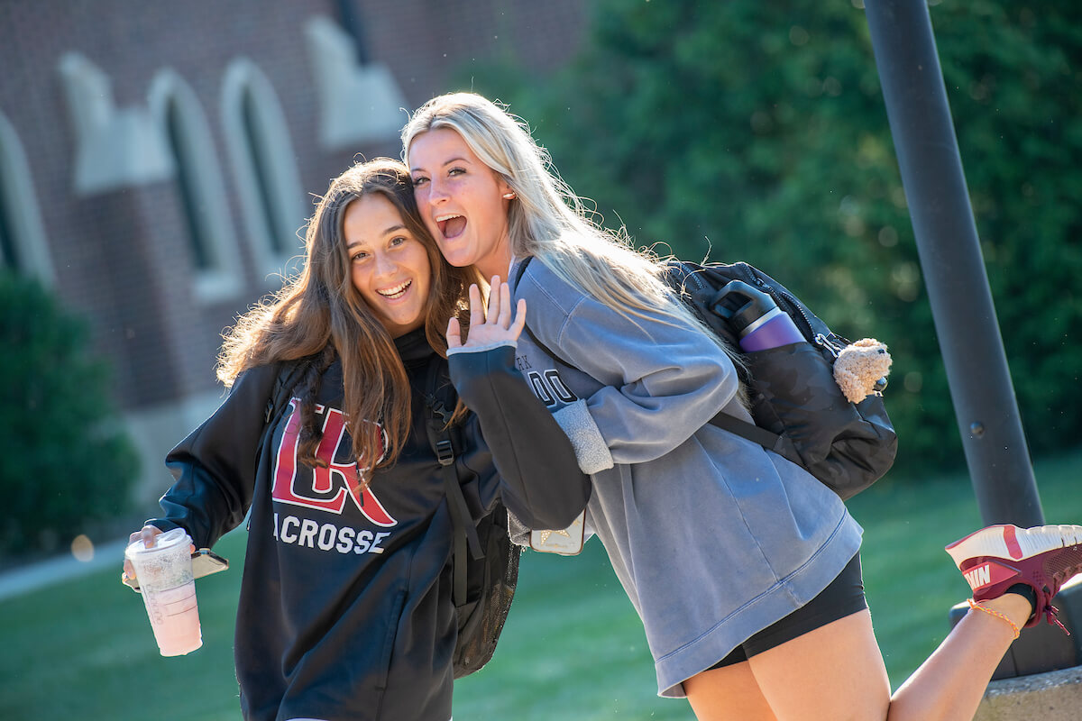 Two students pose in a silly way for camera on campus