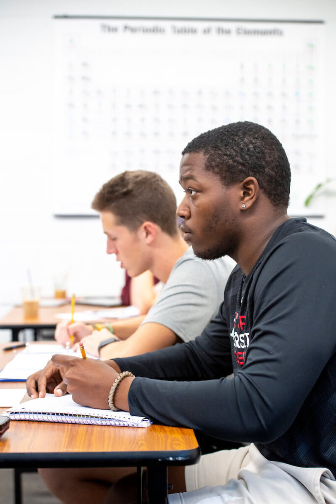 Two students at desk listening to professor lecture during class
