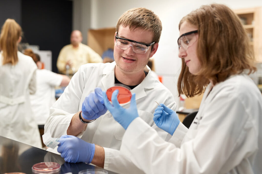 Two students examine petri dish during science lab