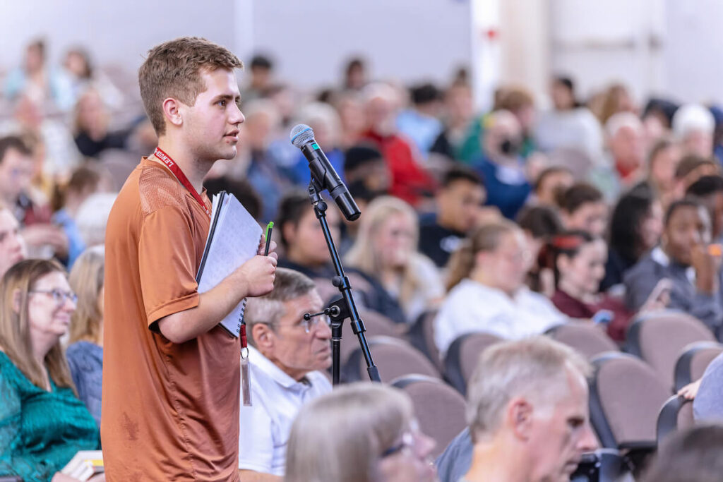A student at microphone within crowd as a question of event speaker